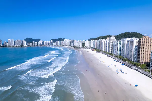 Bu kıyı manzarasında Guaruja, Sao Paulo 'daki Praia da Pitangueiras, açık mavi suların altın kumlarla buluştuğu ve kıyı boyunca uzanan yüksek binalar ziyaretçileri plajın tadını çıkarmaya davet ediyor..