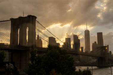 Brooklyn Köprüsü çarpıcı bir gün batımına karşı olağanüstü bir şekilde duruyor. Pembe ve mor bir gökyüzü Doğu Nehri üzerindeki tarihi mimariyi aydınlatıyor..