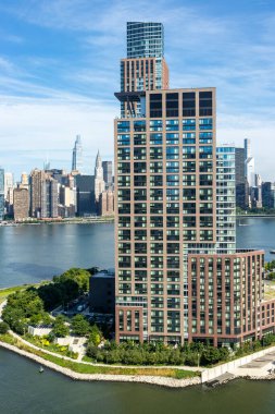Görüntü, New York 'taki parlak cam gökdelenleri yakalıyor. Açık bir öğleden sonra güneş ışığını yansıtıyor. Modern tasarımı kentsel manzaralarla harmanlıyor..