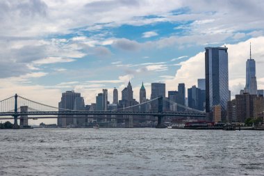 New York 'ta güneşli bir günde gökyüzü, modern binaların ve açık mavi gökyüzünün ortasında şehir hayatının özünü yansıtan One World Trade Center' la ünlüdür..