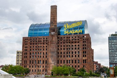 The Domino Sugar Factory showcases a blend of history and modernity in Brooklyn, New York, featuring its prominent smokestack and contemporary design under an overcast sky. clipart