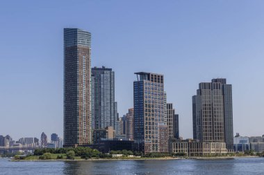 Görüntü, New York 'taki parlak cam gökdelenleri yakalıyor. Açık bir öğleden sonra güneş ışığını yansıtıyor. Modern tasarımı kentsel manzaralarla harmanlıyor..