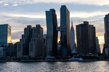 Güneş batarken, altın saat Manhattan 'ın silueti üzerinde sıcak bir ışık saçıyor, gökdelenlerin parlak gökdelenlerinin belirgin siluetlerini aydınlatıyor..