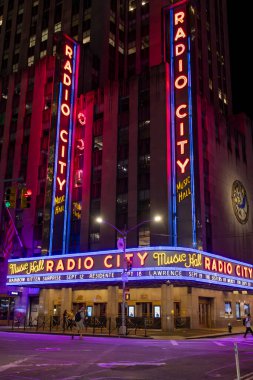 Radio City Music Hall 'un parlak neon ışığı gece gökyüzüne karşı parlıyor, ziyaretçileri New York' un göbeğindeki ünlü performanslarını ve etkinliklerini deneyimlemeye çekiyor..