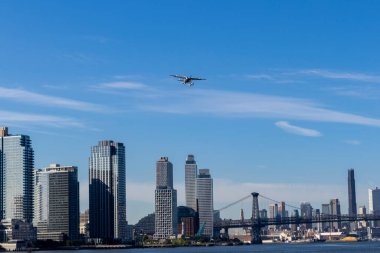 A hydro plane navigates above the iconic New York skyline, showcasing the city's distinctive architecture against a backdrop of clear blue skies. clipart