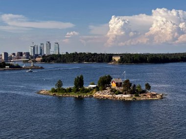 Güneşli bir günde arka planında Helsinki 'nin ufuk çizgisi olan küçük Finlandiya adası