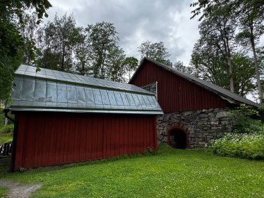 Fagervik, Finlandiya: Finlandiya 'da taştan temelleri ve metal çatıları olan iki kırmızı ahır, bulutlu yaz gökyüzü.