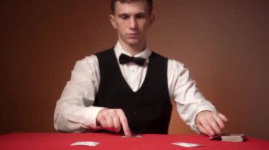 Kafkasyalı genç kumarhane satıcısı kartları kırmızı masaya koyar, yakın plan eller..