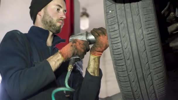 年轻的汽车修理工在汽车上安装了一个轮子 汽车修理店 — 图库视频影像