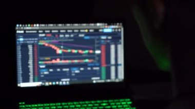 A man works with cryptocurrency on a laptop. dark room. close-up