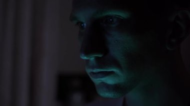Portrait of a male hacker. nervous look. close-up. blue light.
