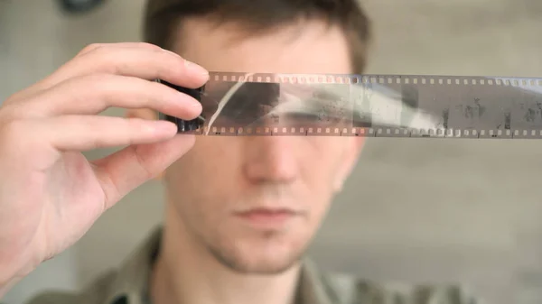 A young photo lab technician looks at an old archival film. close-up