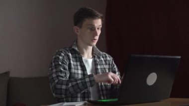 Gözlüklü genç bir adam dizüstü bilgisayarla çalışmaya başlar. sürgülü kamera
