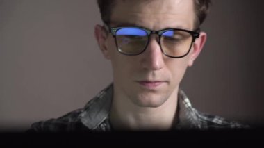 Genç yorgun adam kötü bir iş gününden sonra laptopunu kapatır. Gözlüklerini çıkarıyor ve yorgunluktan gözlerini ovuşturuyor. yakın plan.