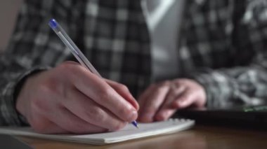Genç bir adam bir not defterine çevrimiçi bir ders not alıyor. uzaklık eğitimi