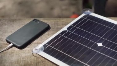Akıllı telefonu taşınabilir güneş paneliyle şarj etmek. kamp