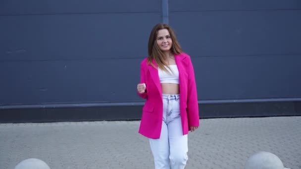 ピンクのジャケットで若い魅力的な白人ブルネットの少女が回転する — ストック動画