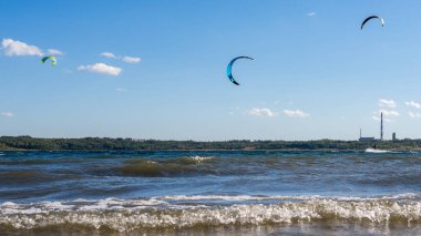 Uçurtmacılar gölün üzerinde uçuyor. Güzel güneşli ve rüzgarlı bir günde uçurtma sörfü (uçurtma)