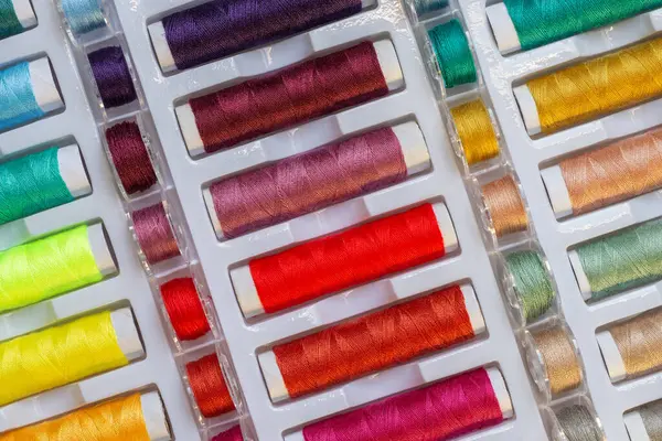 Flat lay view of rainbow threads and plastic bobbins for sewing machines