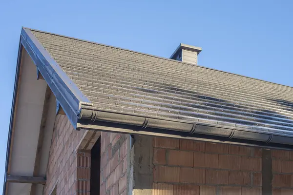 Mavi gökyüzüne karşı yeni bir konutun antrakit renkli çatısı