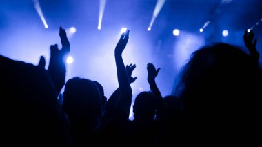 Konser salonu canlı performans sırasında elleri havada müzik hayranlarıyla dolu.