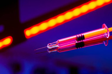 Yansıtıcı yüzeyde parlayan neon şırınga