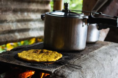 Geleneksel Kolombiya arepası tipik bir Kolombiya çiftlik sobasında kızarıyor. Ahşabı yakıt olarak kullanarak yemek pişirmek. Geleneksel Kolombiya mutfağında düdüklü tencere..