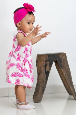 Bebek esmer yürümeyi öğreniyor, sandalyeyi bırakıyor ve dengesini sağlamak için ellerini kaldırıyor.