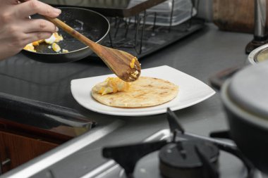 Latin bir kadının arepaya çırpılmış yumurta dökerken çekilmiş detaylı bir fotoğrafı. Tipik Kolombiya kahvaltı hazırlığı.