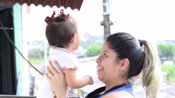 ラティーナの母親は彼女の腕の中で彼女の赤ちゃんを保持しながら 彼女を投げ 彼女と遊ぶ 娘を笑わせる若い女性は — ストック動画