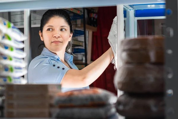 view of a young latina\'s face through a shelf. girl working in a colombian corner store.