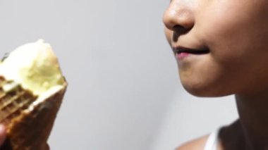 detailed view of a little girl's mouth, licking the ice cream cone. white background