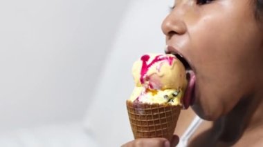 close-up of a little girl's face, brunette latina licking ice cream. white background