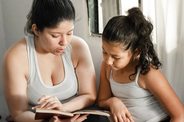 Madre Latina Enseñando Pequeña Hija Importancia Leer Sentada Cama — Foto de Stock