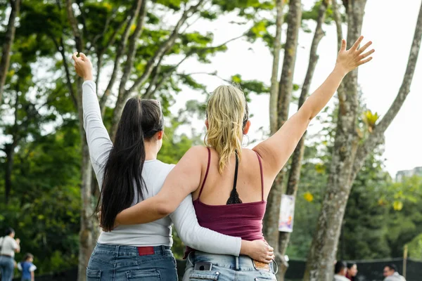 Две Латиноамериканки Обнимающиеся Парке Поднимают Руки Праздничном Жесте — стоковое фото