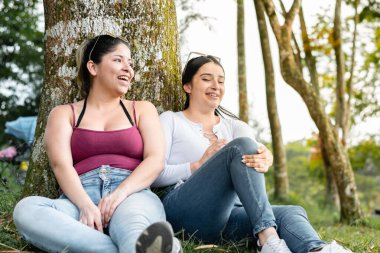 Kızlar bir ağacın yanında oturup sohbet eder ve çok gülerler. dostluk kavramı