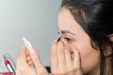 Kaşlarına küçük bir fırçayla makyaj yapan Latin bir kadının detaylı görüntüsü.