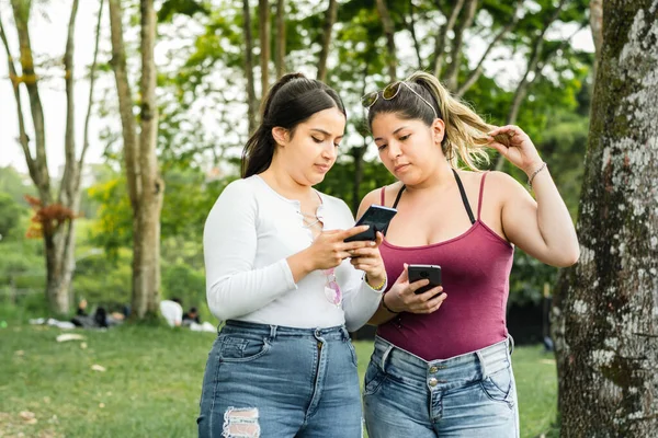 Deux Amis Latins Dans Parc Promenant Regardant Leurs Téléphones Portables — Photo