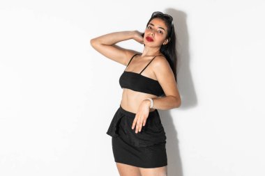 Kahverengi tenli güzel bir Latin kadının portresi. Beyaz bir arka planda poz veriyor ve ileriye bakıyor.