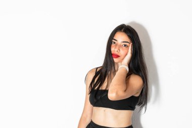 Güzel esmer Latin model. Bir eli kafasında poz veriyor. Önüne bakıyor.