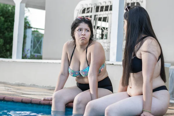 Две Молодые Латиноамериканки Сидят Берегу Бассейна Ногами Воде Болтают Друг — стоковое фото