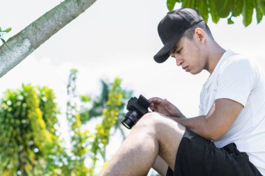 Genç Latin adam, sahada oturmuş sosyal medya kamerasından kaydettiği içeriği izliyor..