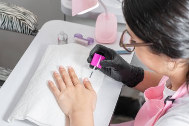 Maniküre başlamadan önce nemlendirici süren genç bir kadının üst görüntüsü.