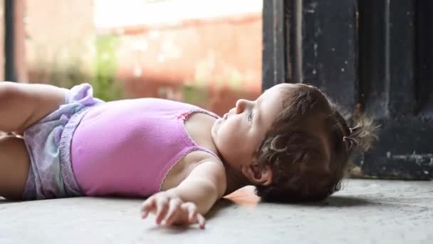美丽的拉丁婴儿躺在地板上 抬起头来朝旁边滚去 — 图库视频影像
