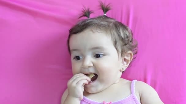 ピンクのマットレスに横たわる小さな白人ベビーガールのクローズアップ フレンチフライを食べる — ストック動画