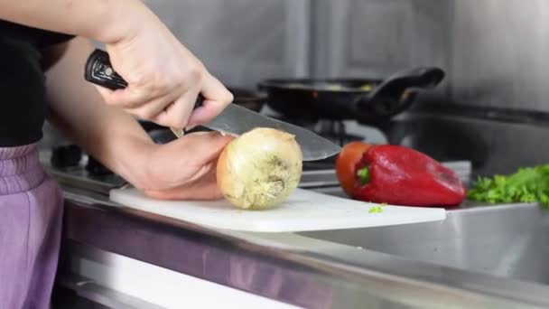 在厨房的一块白板上 一个女人紧握着刀 把一个鸡蛋洋葱劈成两半的特写镜头 — 图库视频影像