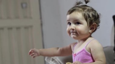 Kafkasyalı güzel Latin kız bebek gülümserken el sallıyor ve elini kaldırıyor.