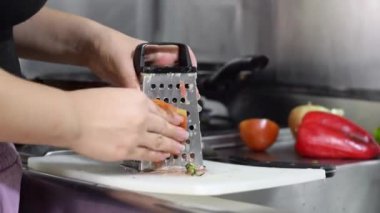 Domatesleri küçük parçalara ayırmak için öğütücüleri tutan bir kadının ellerini yakın plan yapın ve sonra güveci hazırlayın..