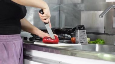 Mutfakta elinde bıçakla güveç hazırlamak için biberi ikiye bölen kadının detaylı görüntüsü..