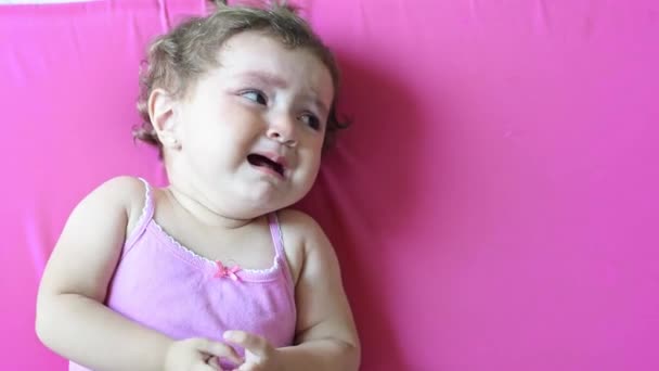 リトルラティナの赤ん坊はピンクのベッドに横たわり 背中に横たわって泣いている — ストック動画